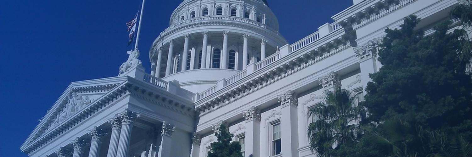 White neoclassical government capitol building with a columned dome against a deep blue sky