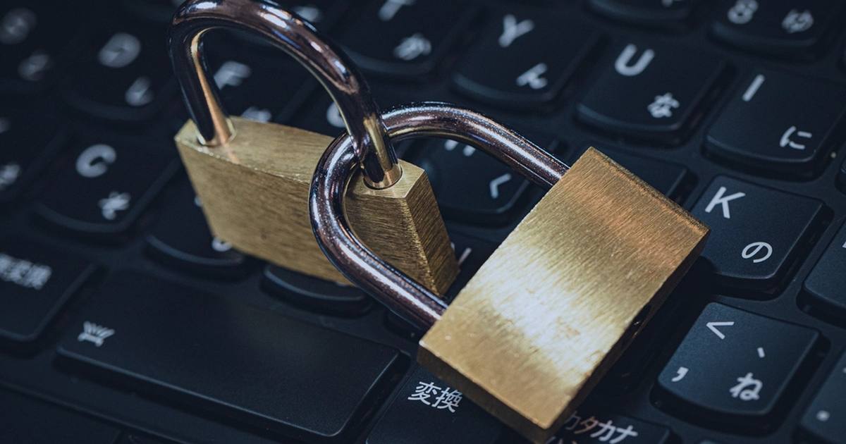 Two brass padlocks resting on a black computer keyboard